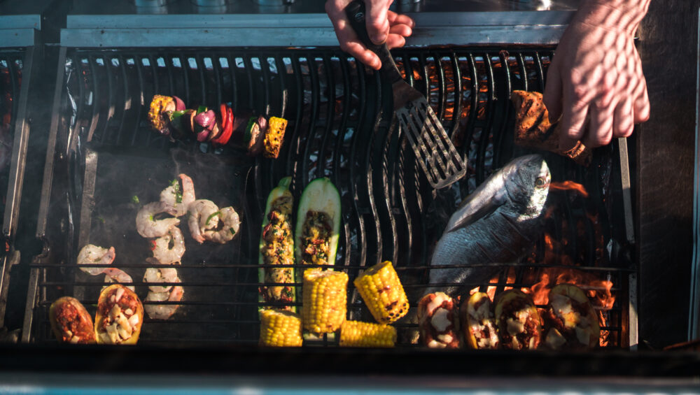 záběr zhora na různé pochutiny na grillu - krevety, ryba, kukuřice, zelenina a špízy